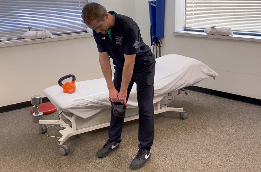 Physical Therapist showing how to raise a kettle bell safely